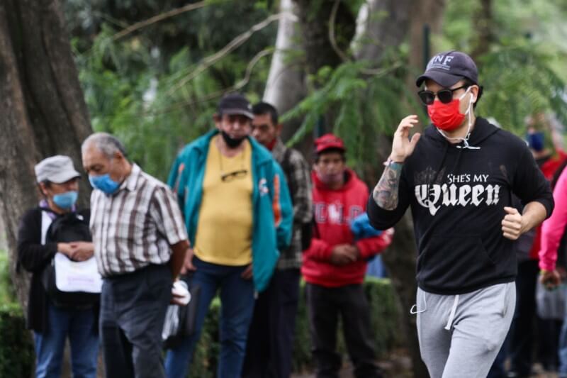 hombre hace ejercicio en un parque donde pasean más personas