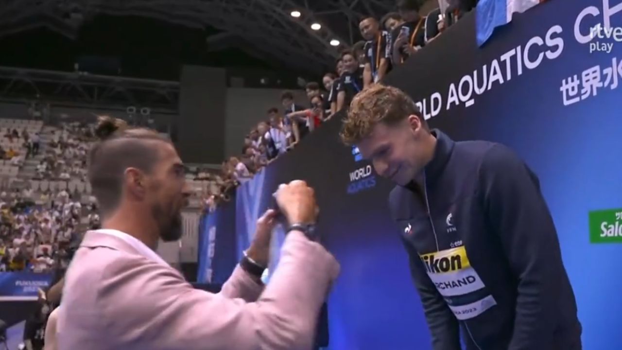 Leon Marchand rompe el último récord mundial que le quedaba a Michael Phelps; el "Tiburón de Baltimore" lo celebra y entrega la medalla de vencedor al francés.