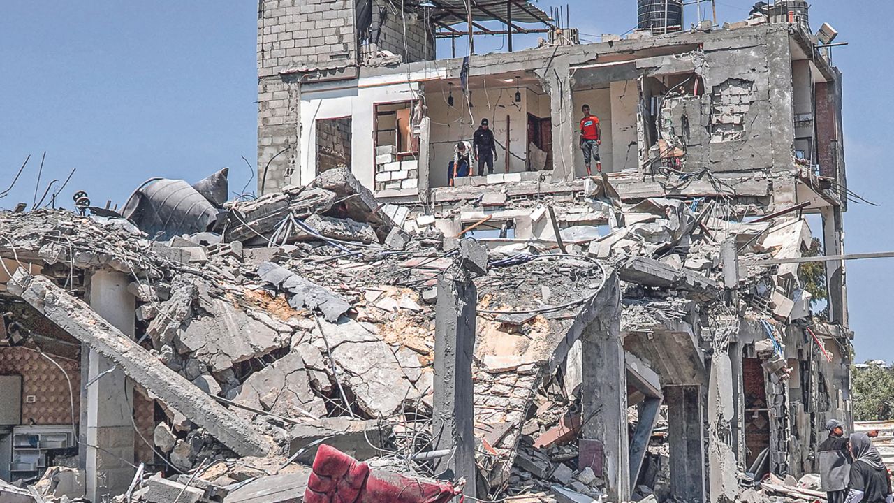 DAÑOS. Varias personas observaban ayer un muro destruido en un campo para refugiados palestinos, en el centro de la Franja de Gaza.