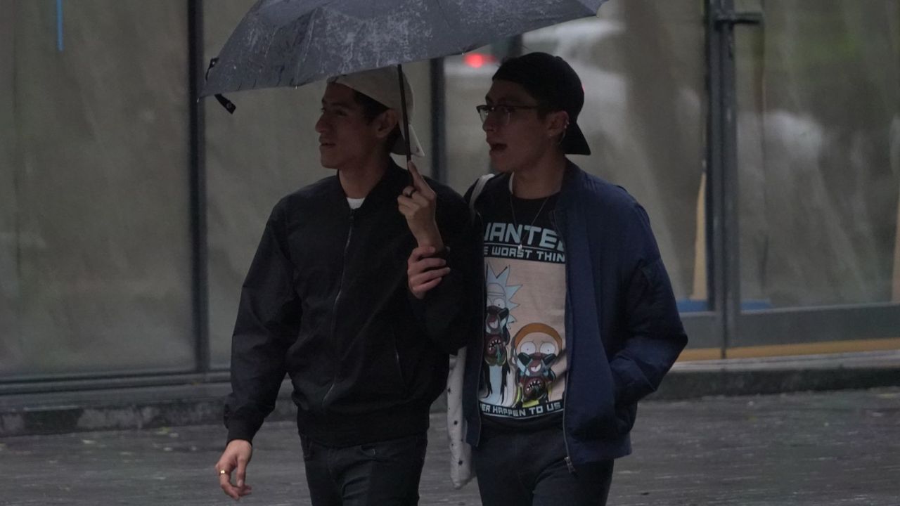 Dos personas caminando bajo la lluvia provocada por Frente Frío en México.