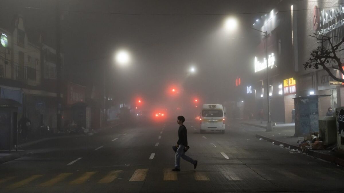 Un peatón cruzando una avenida ante la presencia de un banco de neblina ante la alerta por frío.