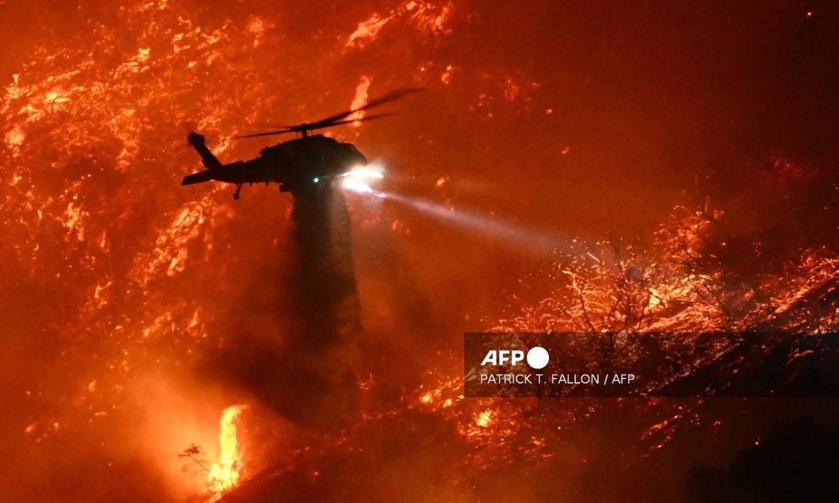 Un helicóptero de extinción de incendios arroja agua mientras el incendio de Palisades, Los Ángeles, crece.