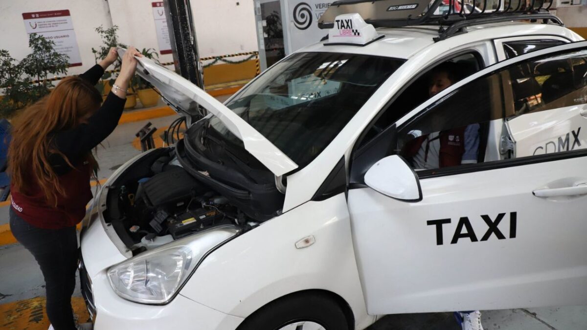 Empleados realizan verificación vehicular a un taxi de la CDMX.