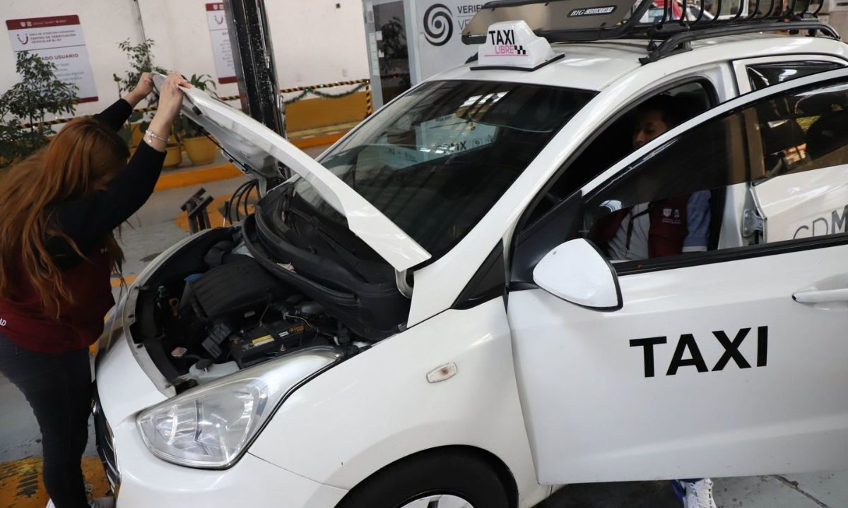 Empleados realizan verificación vehicular a un taxi de la CDMX.