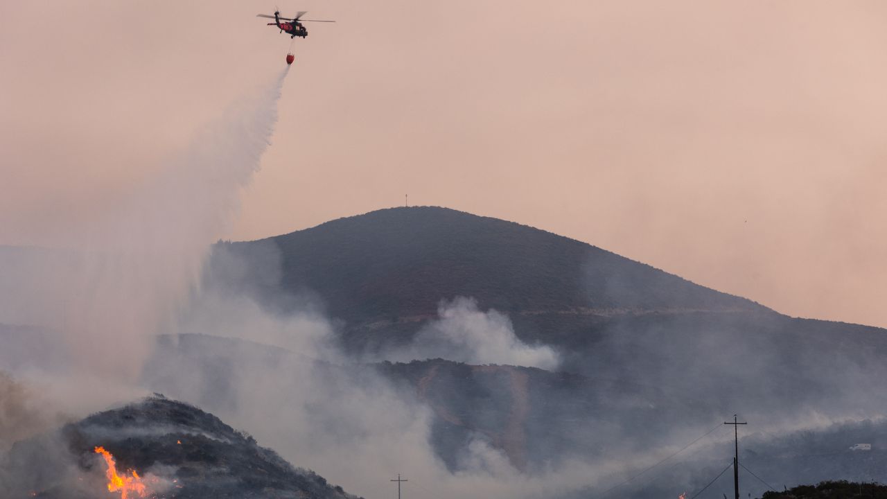 Un helicóptero arroja agua sobre el incendio de la frontera en San Diego, California