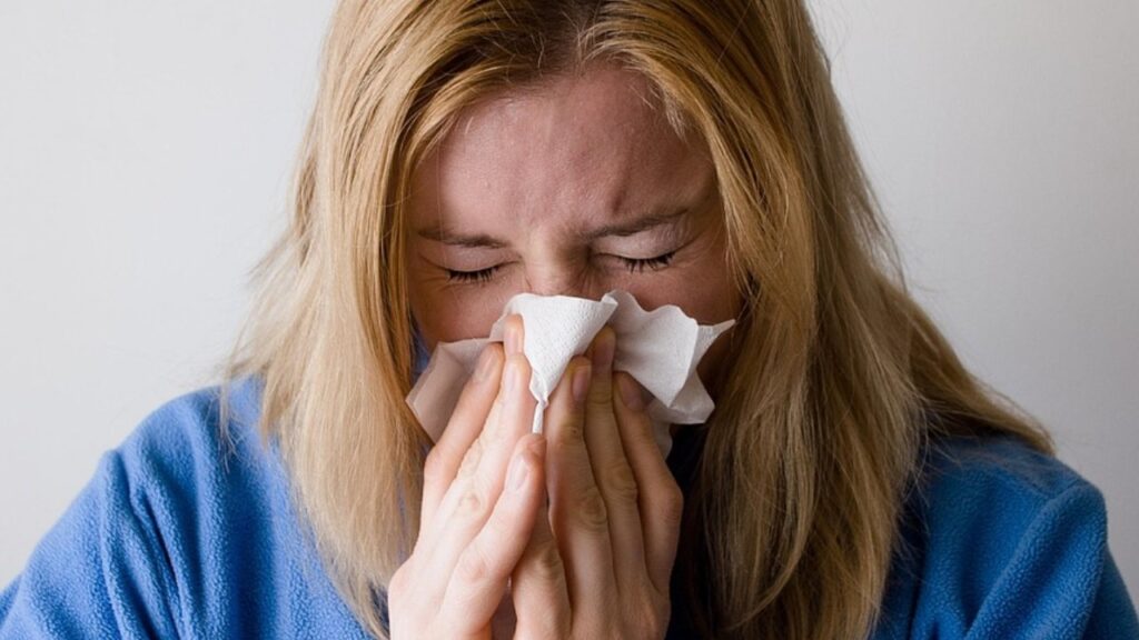 Una mujer sufre un cuadro de gripe, por lo que utiliza un pañuelo para el escurrimiento nasal.