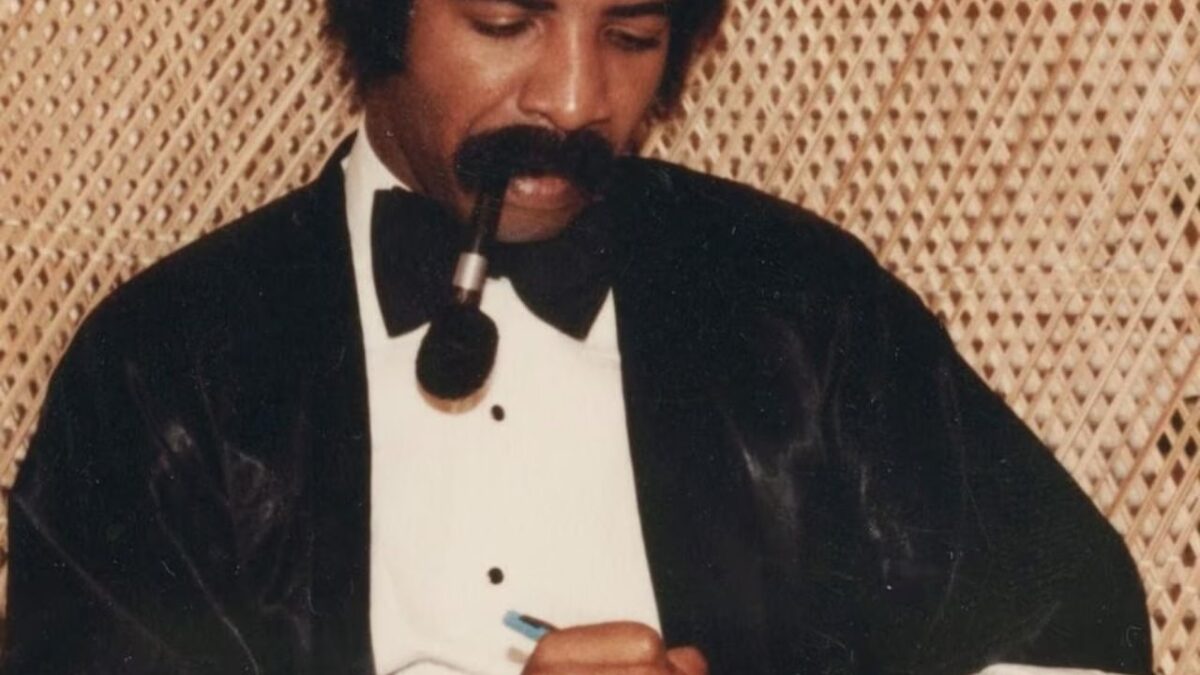 La famosa imagen de la portada de More Life muestra a Dennis Graham, el padre de Drake, con un esmoquin mientras escribe con una pluma. La imagen refuerza la temática de legado y celebración familiar que atraviesa el proyecto.