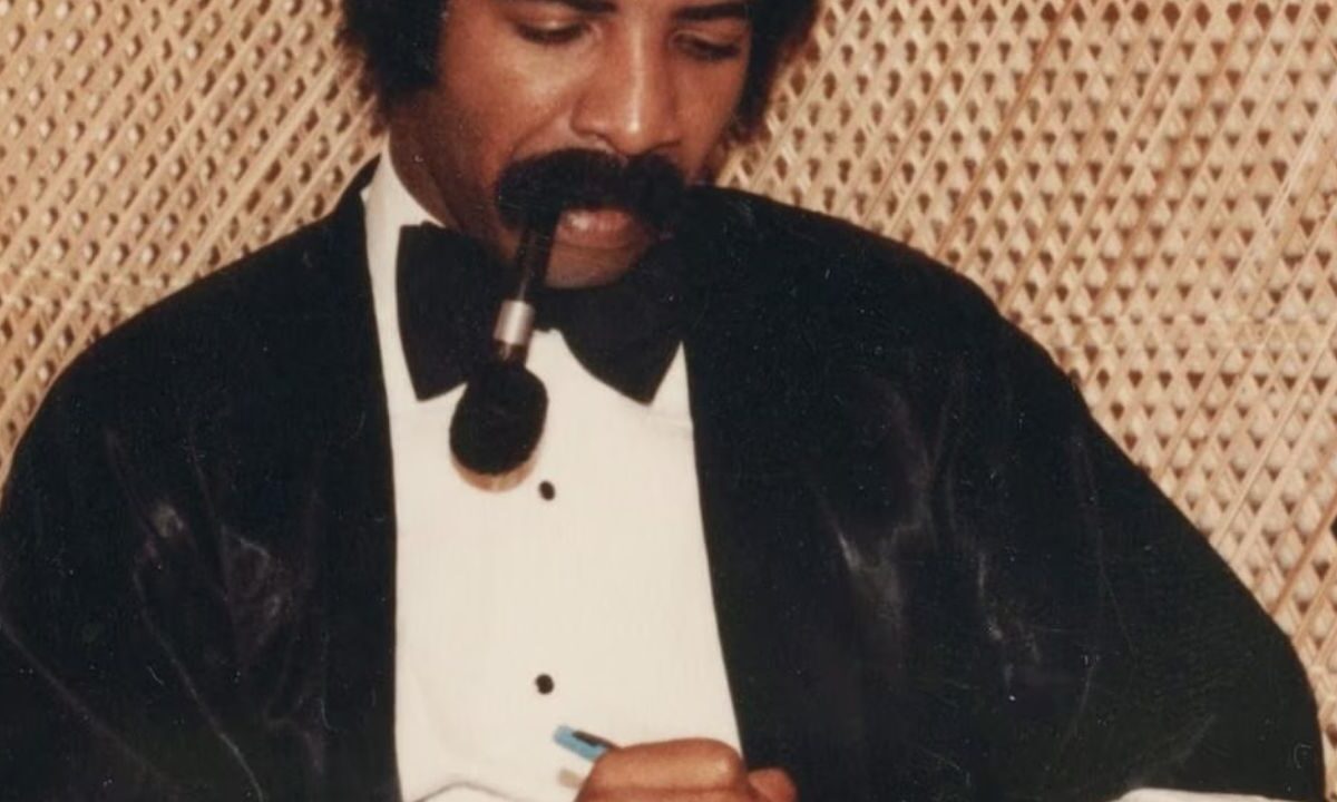 La famosa imagen de la portada de More Life muestra a Dennis Graham, el padre de Drake, con un esmoquin mientras escribe con una pluma. La imagen refuerza la temática de legado y celebración familiar que atraviesa el proyecto.