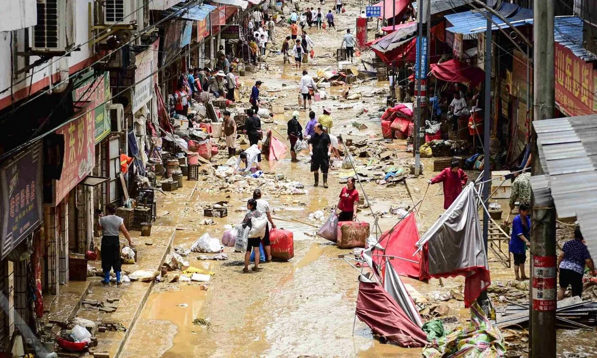 Personas caminan con sus pertenencias en una zona inundada en Congjiang, provincia de Guizhou, suroeste de China